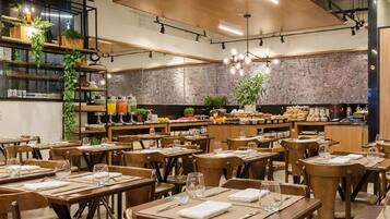A spacious restaurant with multiple tables and chairs, a high ceiling with wooden panels, and a kitchen area visible in the background.