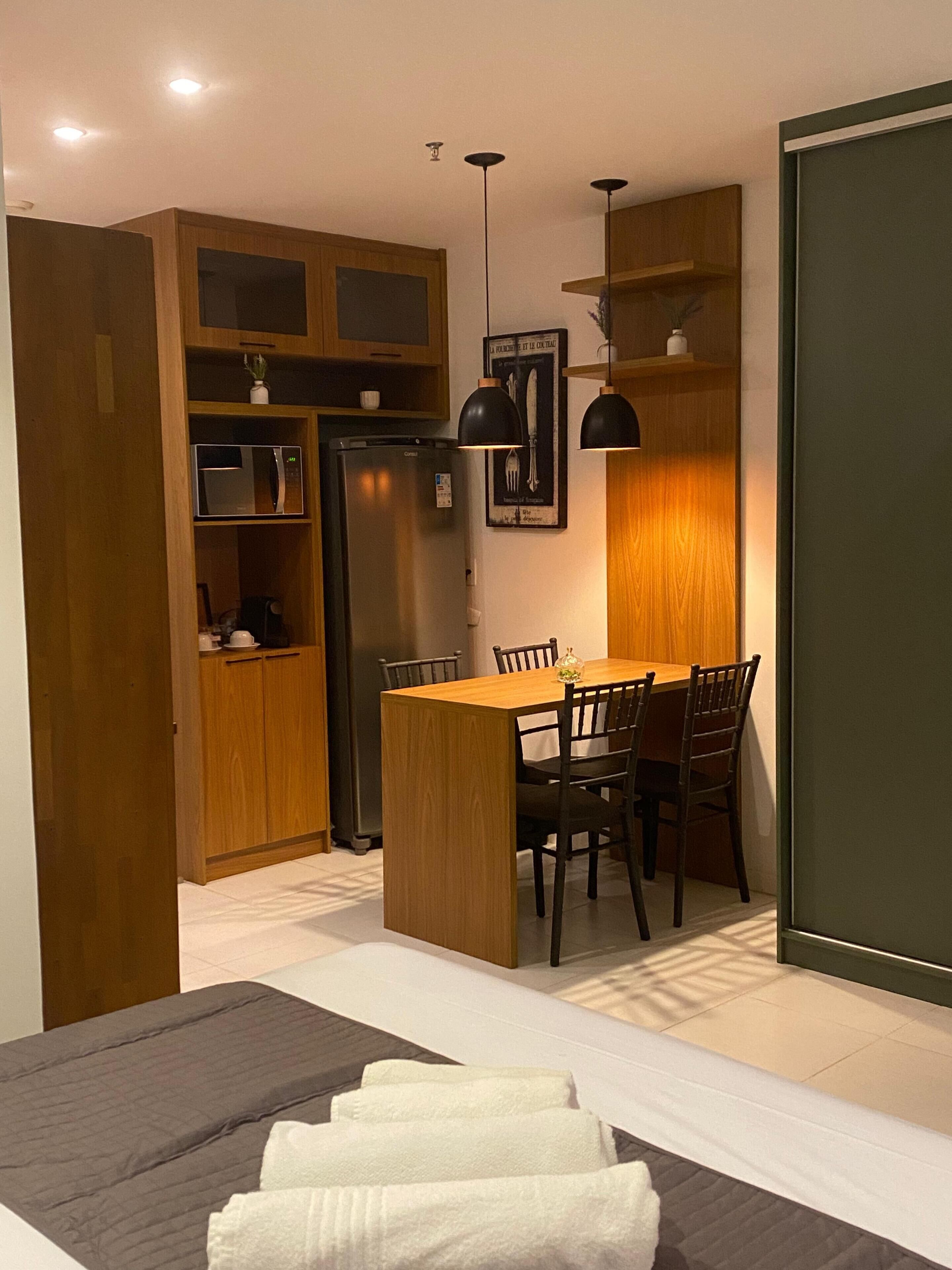 A compact kitchen with a dining table, chairs, and a refrigerator.