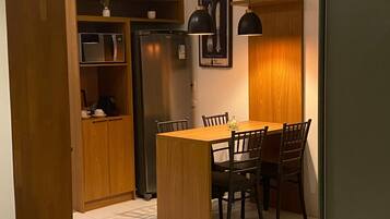 A compact kitchen with a dining table, chairs, and a refrigerator.