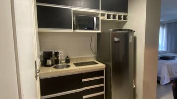 Una cocina compacta equipada con microondas, cafetera y refrigerador.