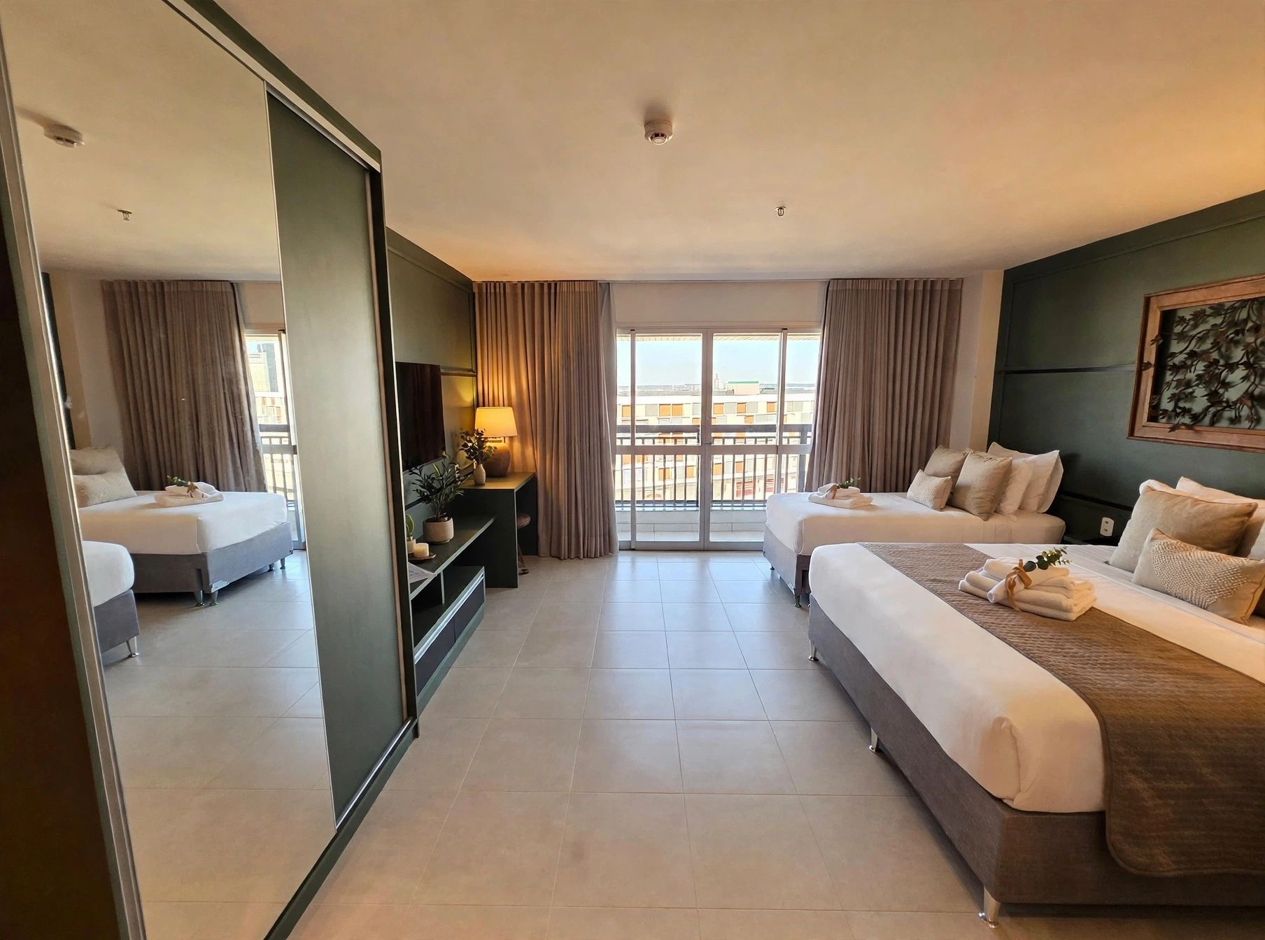Una habitación de hotel con una cama, un sofá, un escritorio y un ventanal grande.