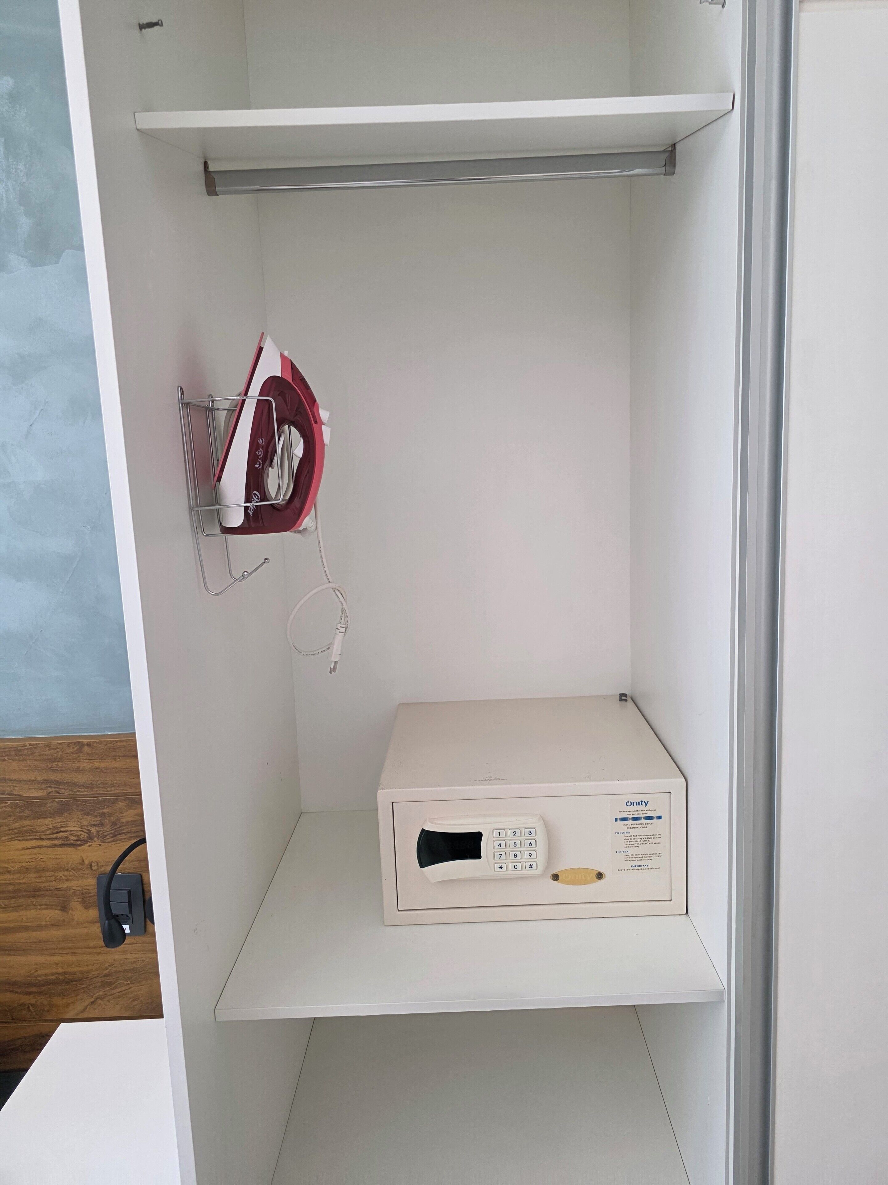 A white cabinet with a microwave, a shelf, and a hanging rack with a red appliance.