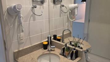 A bathroom with a sink, mirrors, a hairdryer, and a toilet.