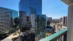 A high-rise building with a curved glass facade, surrounded by other modern buildings, and a view of a parking area below. - Flats Premium com vista Incrível no hotel Vision (Brasília)