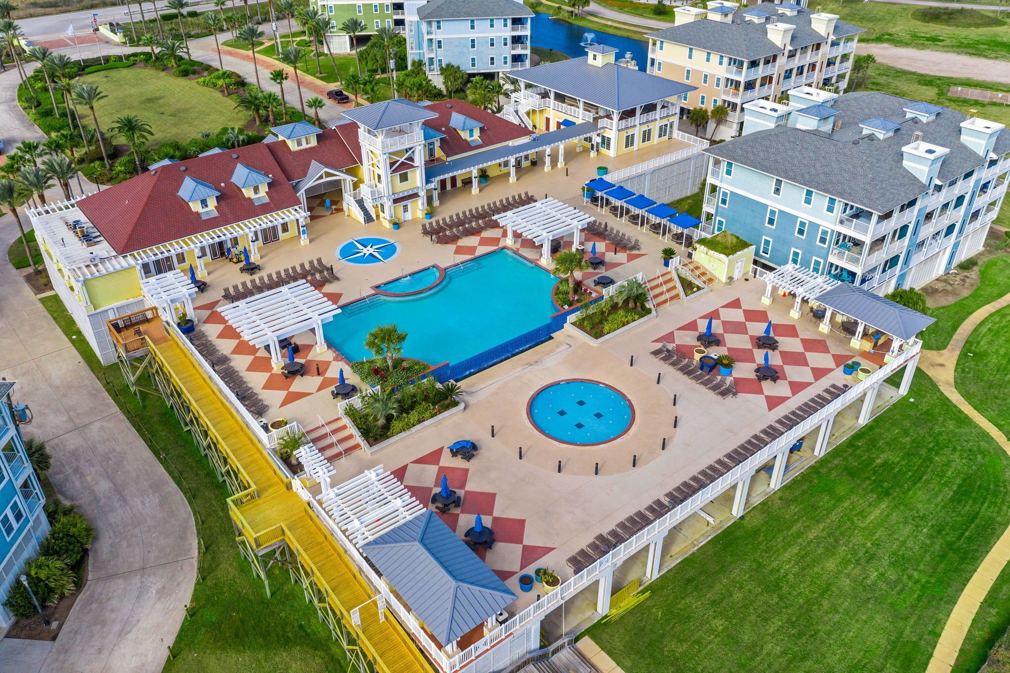 A resort with a large pool, outdoor seating areas, and multiple buildings with balconies.