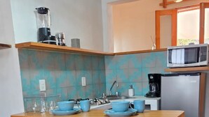 Een keuken met een centraal eiland, barstoelen, een magnetron en een koelkast.