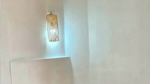 Een slaapkamer met een bed, nachtkastje, lamp en een flesje aromatische diffuser.