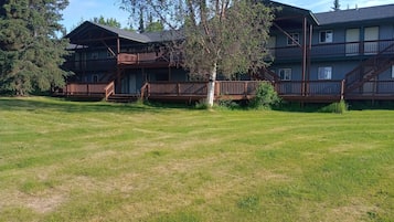 A two-story building with a wooden deck and a grassy yard.