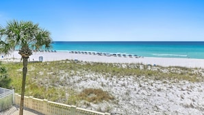 A beach with a palm tree, a fence, and a clear blue sky. - Aqua Villa 302 (Fort Walton Beach)