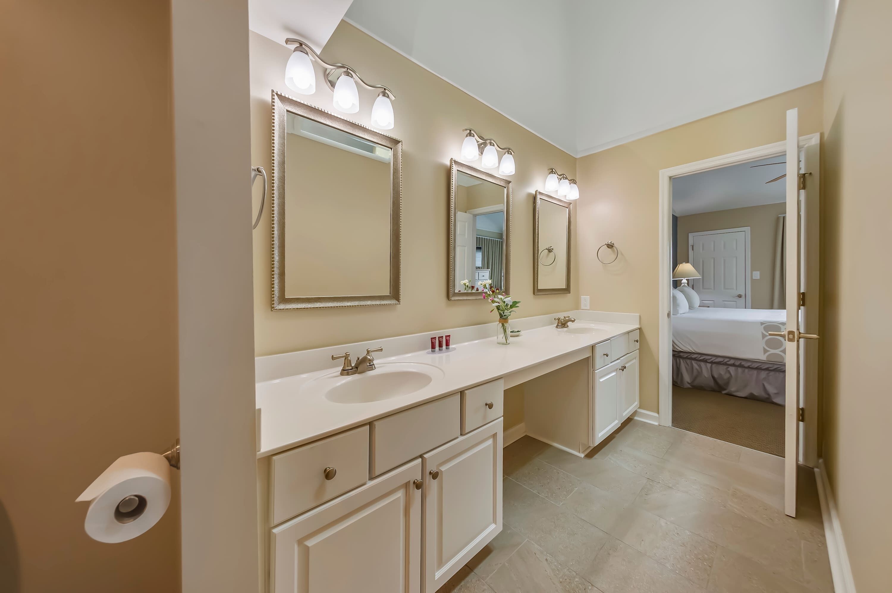 A bathroom with a double sink, two mirrors, and a toilet paper holder.