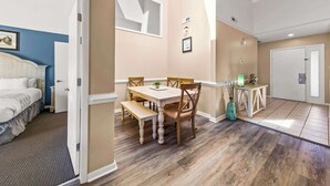 Een hotelkamer met een bed, een eettafel met stoelen, een kitchenette en een deur naar een andere kamer.
