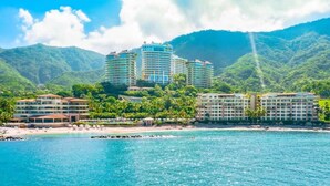 A coastal hotel with multiple buildings, a beach, and a mountainous backdrop. - Garza Blanca Resort Junior Panoramic Suite in Puerto Vallarta 1 Bedroom, 1 Bath. (Puerto Vallarta)