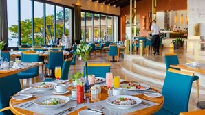 A modern dining area with round tables, blue chairs, and a view of the outdoors. - Garza Blanca Resort Junior Panoramic Suite in Puerto Vallarta 1 Bedroom, 1 Bath. (Puerto Vallarta)