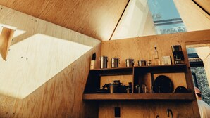 Ein modernes Interieur mit Holzwänden und einer geneigten Decke, ein Küchenbereich mit Kochutensilien und ein Blick durch ein Oberlicht.