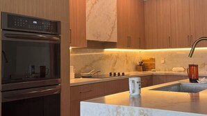 Une cuisine moderne avec des meubles en bois, un plan de travail en marbre et des appareils électroménagers en acier inoxydable.