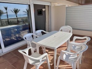 A balcony with a table and chairs, a view of the ocean, and a door leading to another room. - Beachfront apartment with spectacular sea views (Segur de Calafell)