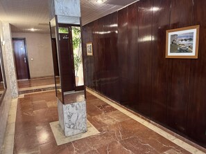 A hallway with a marble column, wooden panel walls, and a framed picture. - Beachfront apartment with spectacular sea views (Segur de Calafell)