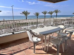 A terrace with a table and chairs, a railing, and a view of the beach and ocean. - Beachfront apartment with spectacular sea views (Segur de Calafell)