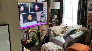 Een woonkamer met een bank, een klein tafeltje, een televisie en diverse decoraties.