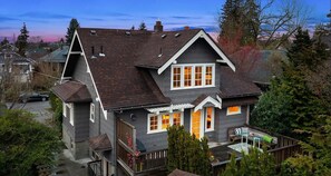 Ein zweistöckiges Haus mit einem steilen Satteldach, einer Veranda und einer sichtbaren Garage.