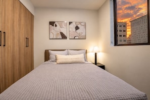 A bedroom with a bed, a nightstand, a lamp, and a window with a cityscape view. - F1008 - Modern Corner 1-Bdr Apt with Pool & Gym in Miami Downtown (Miami)