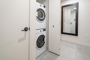 A laundry room with two front-loading washing machines and a mirror on the wall. - F1008 - Modern Corner 1-Bdr Apt with Pool & Gym in Miami Downtown (Miami)