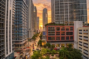 A high-rise building with a prominent 'M' logo, surrounded by other tall buildings, a busy street, and a sunset. - F1008 - Modern Corner 1-Bdr Apt with Pool & Gym in Miami Downtown (Miami)