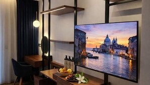 Quarto de hotel moderno com escrivaninha de madeira, televisão de tela plana e vista para o horizonte urbano.