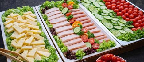 A buffet with various food items including cheese, meat, and vegetables.