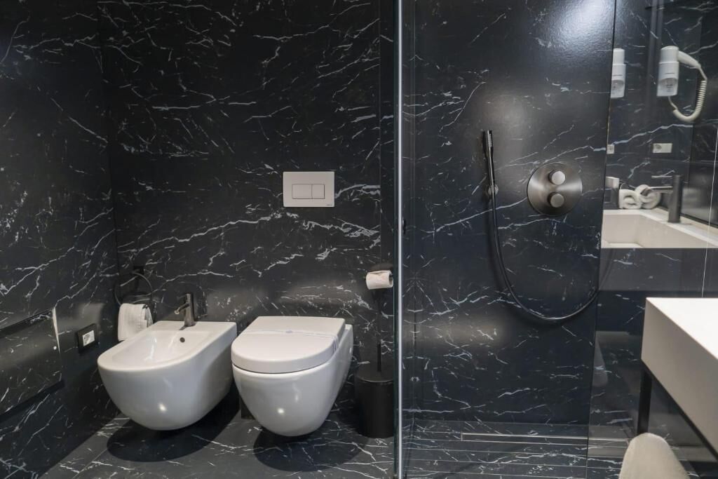 Un baño moderno con bidé, inodoro y zona de ducha con mampara de vidrio.