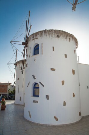 A white building with a circular shape, a small window, and a thatched roof.