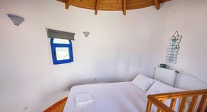 A bedroom with a bed, a window with a blue blind, a radiator, and a wall-mounted decoration.