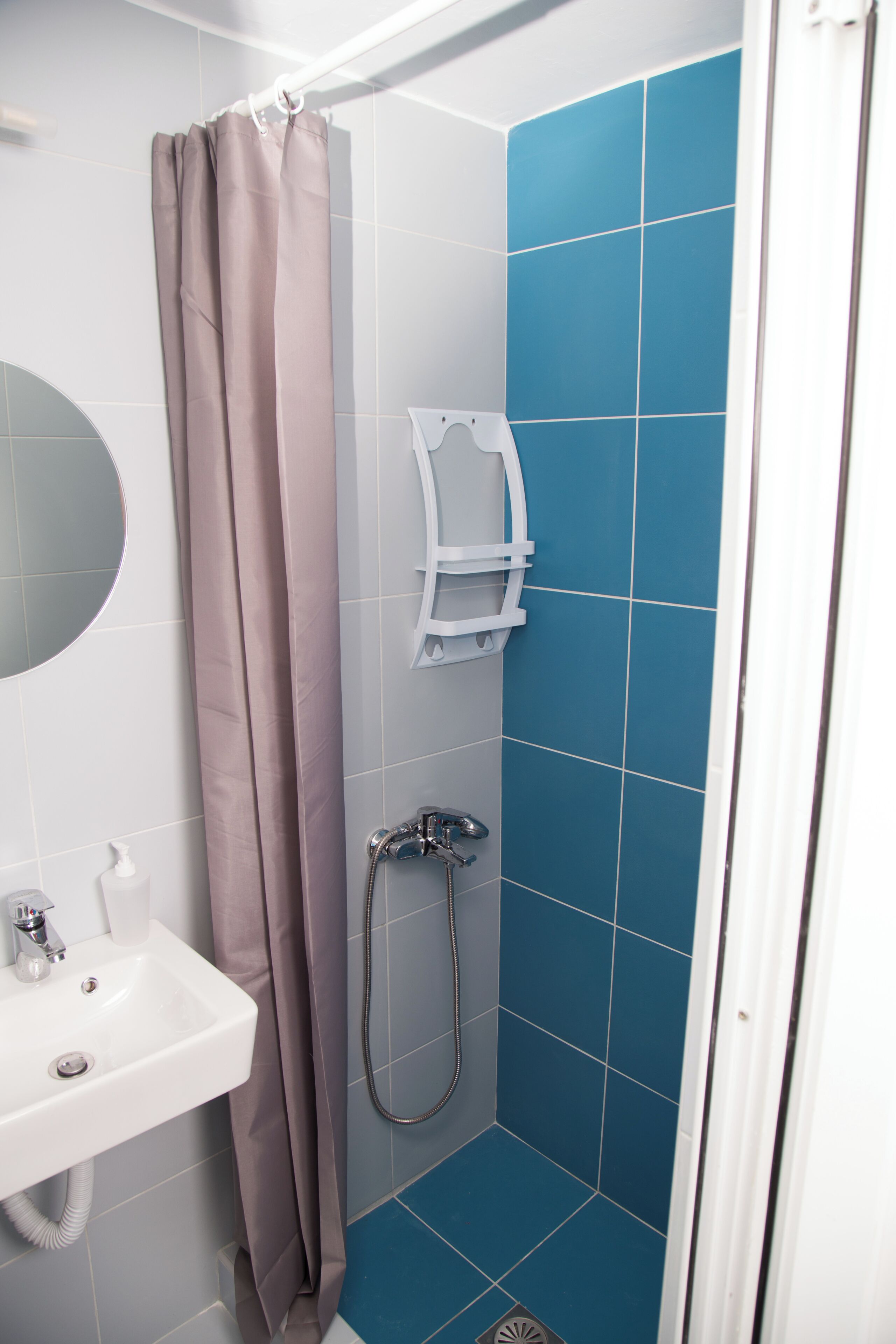 Une salle de bain avec une douche, un lavabo et un miroir.