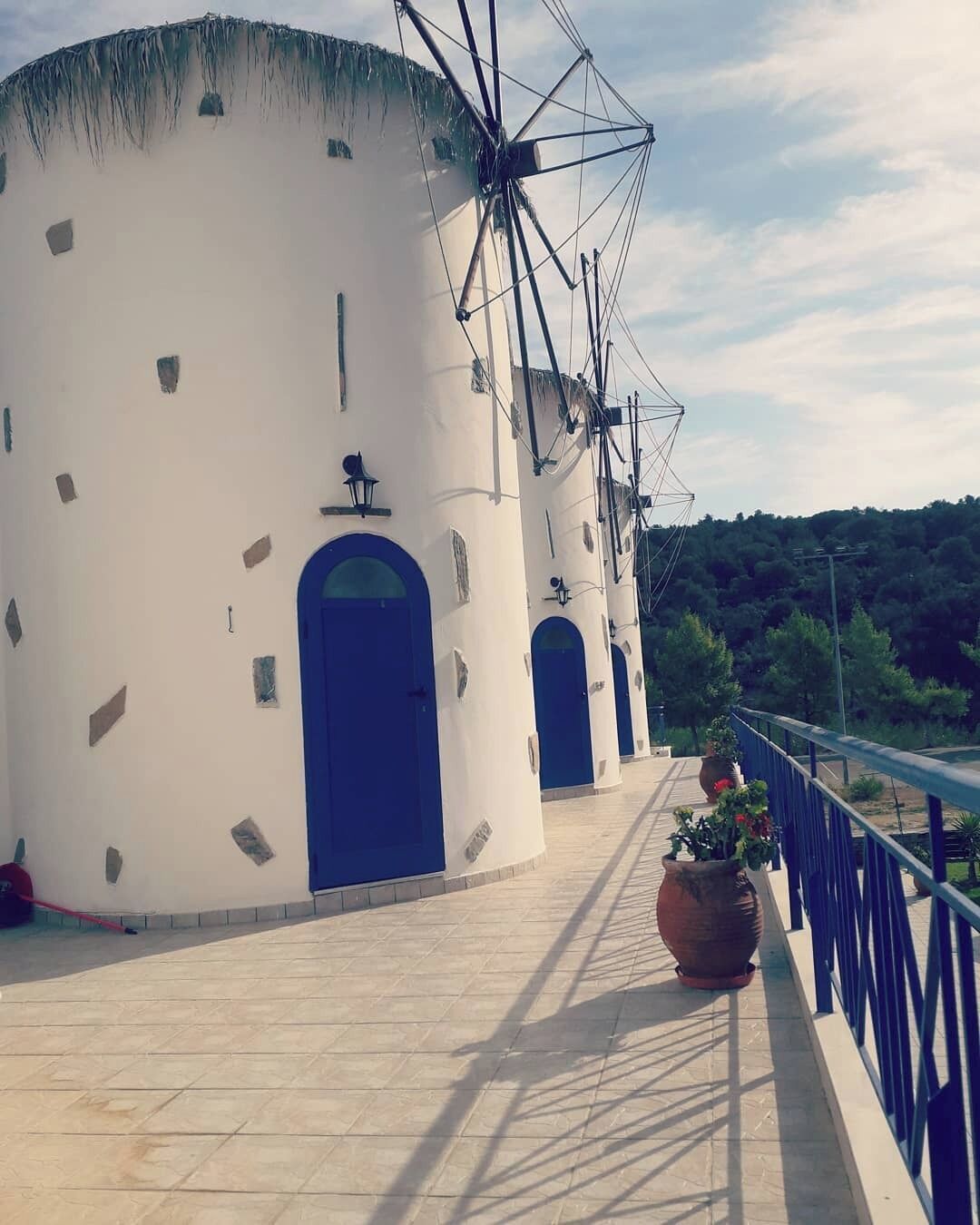 Un edificio con facciata bianca e porte blu, caratterizzato da una struttura a mulino sulla sommità.