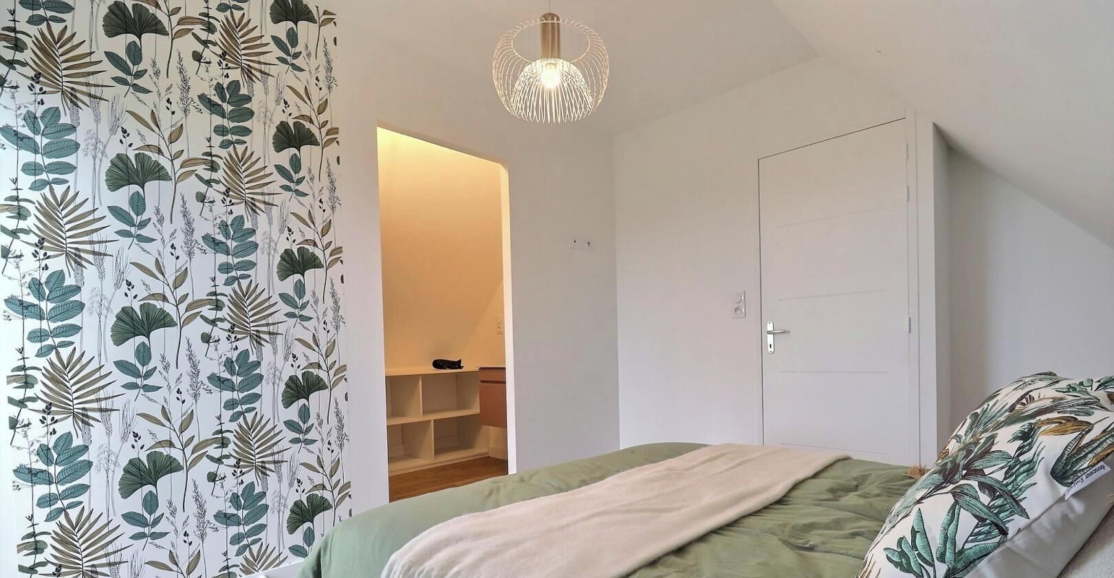 Un dormitorio con cama, armario, lámpara colgante y armario con estantes.