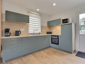 A modern kitchen with grey cabinets, a built-in oven, a microwave, and a coffee maker. - L'Horizon du Mont - SOUGEAL (SOUGEAL)