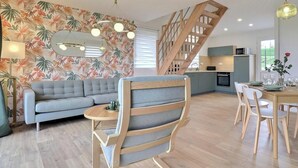 Un salon moderne avec un canapé, une table à manger et une cuisine en arrière-plan.