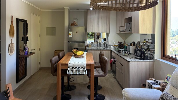 Una cocina moderna con isla integrada, armarios de madera y una lámpara colgante.