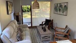 Una sala de estar con sofá, mesa de centro, sillas y una lámpara colgante.