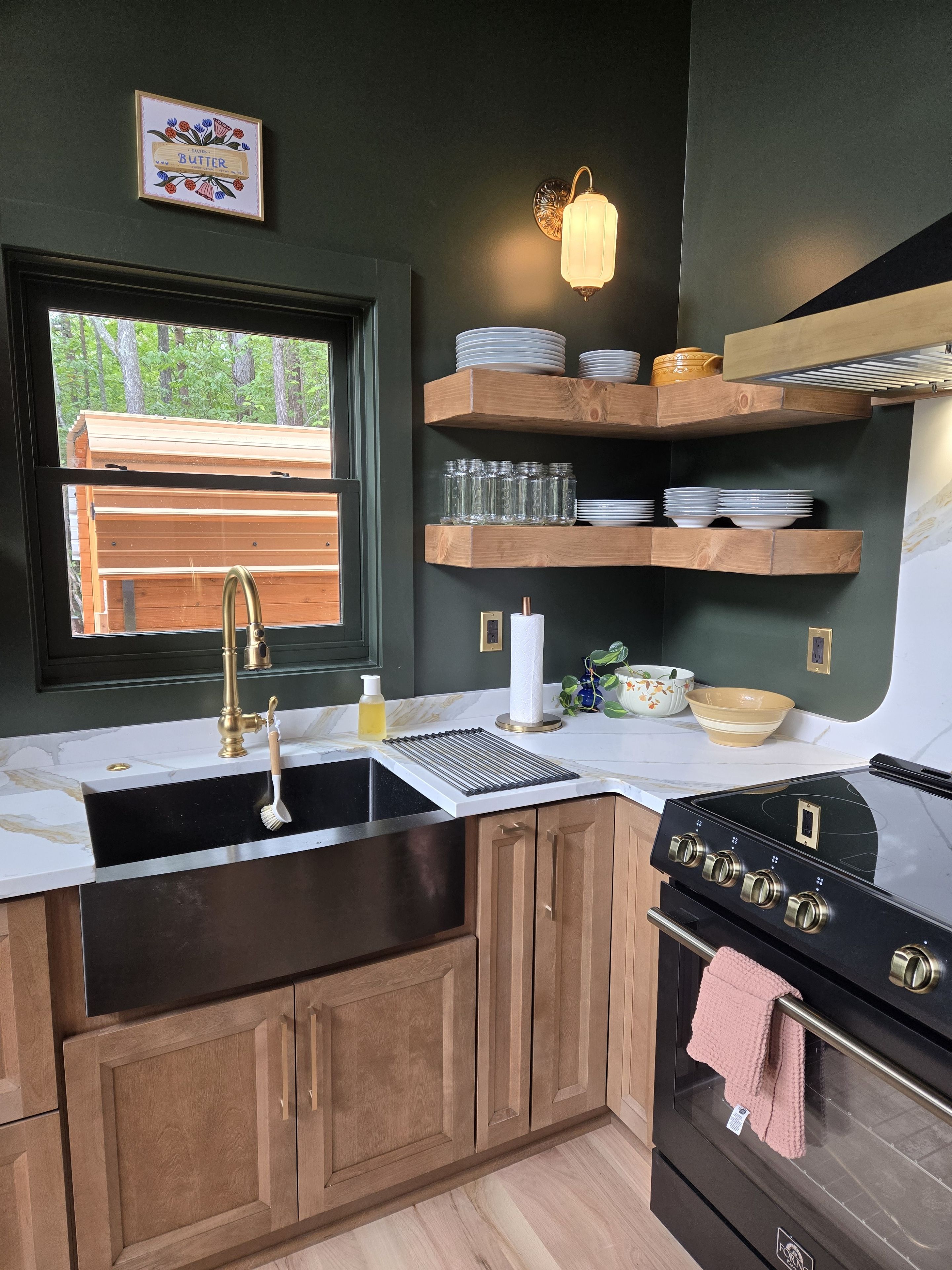 Stylish kitchen with brass accents, open shelving, and forest views