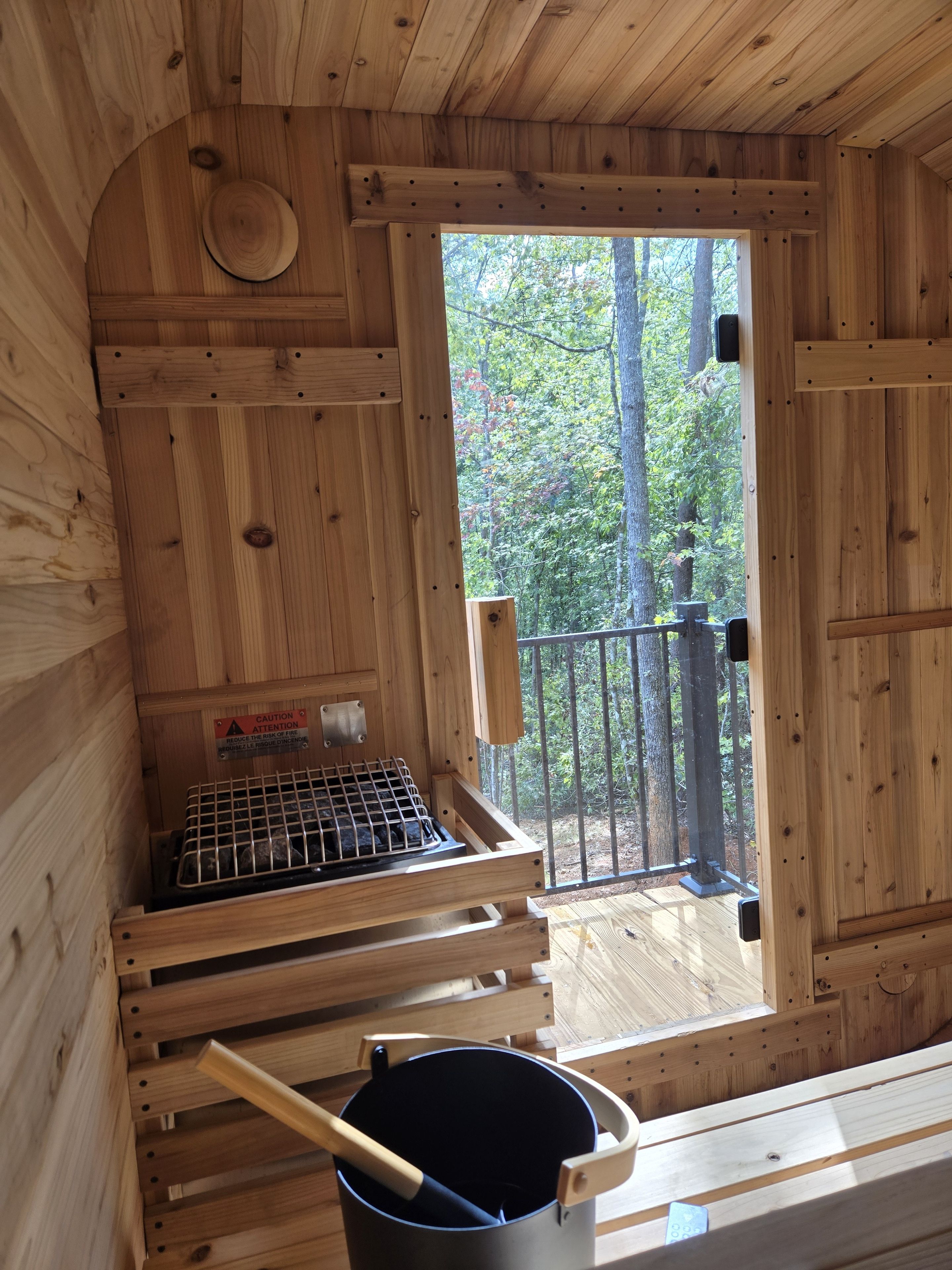 Puinen mökki sisältä, jossa on sauna, varoituskyltti ja näkymä metsään.