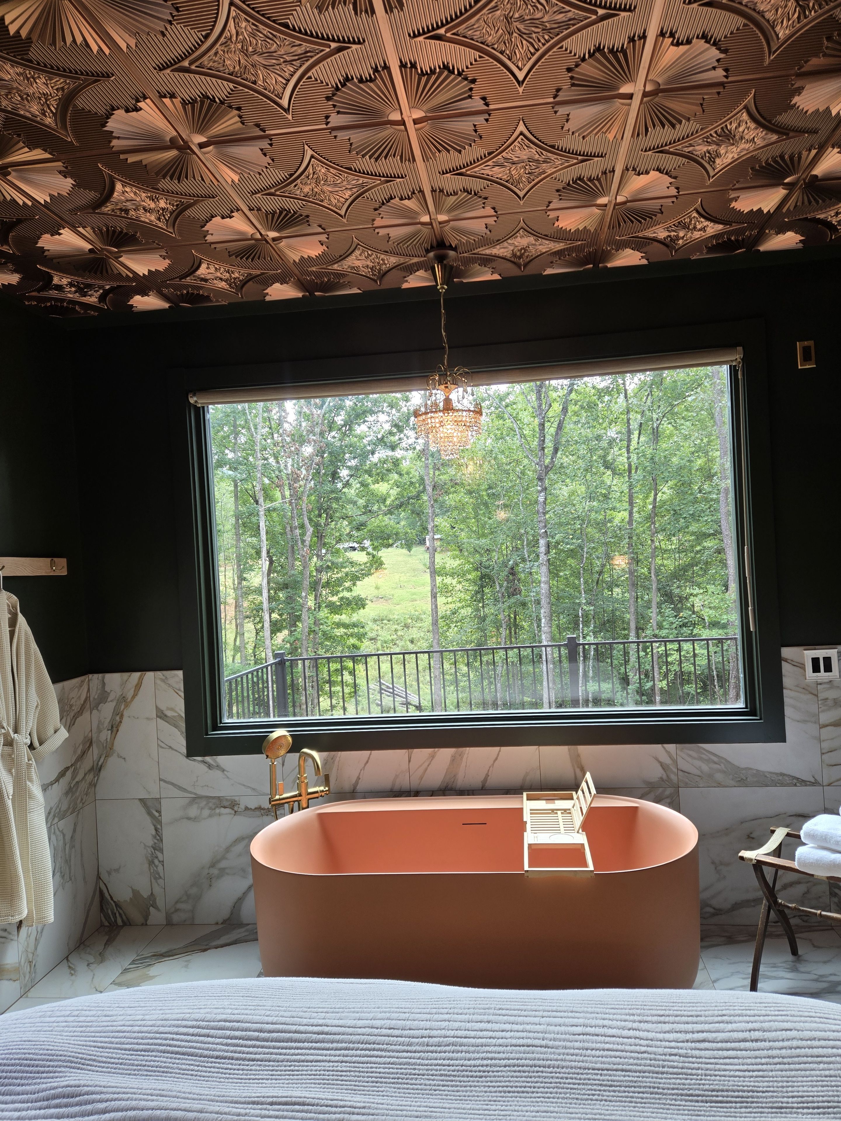 Un baño con un ventanal grande, una bañera y un techo con diseños intrincados.