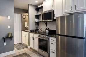 Una cocina moderna con electrodomésticos de acero inoxidable, armarios blancos y encimera negra.