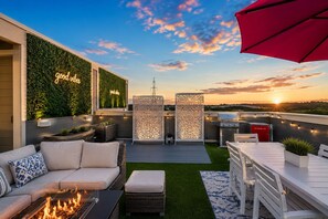 A rooftop patio with a fire feature, outdoor seating, a grill, and a view of the sunset. - Pink Vibes! Hot Tub + Rooftop Views  Sleeps 16 (Nashville)
