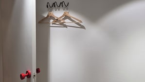Eine weiße Tür mit einem Haken für Kleider und einem roten Türknauf.