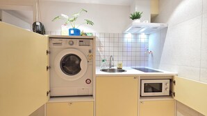 Eine kleine Küche mit Waschmaschine, Spüle und Mikrowelle.
