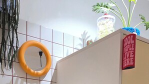 Ein alter Kühlschrank mit McDonald's-Logo, ein gelber Wasserkocher und ein Schild mit der Aufschrift 'COOL PEOPLE LIVE HERE'.