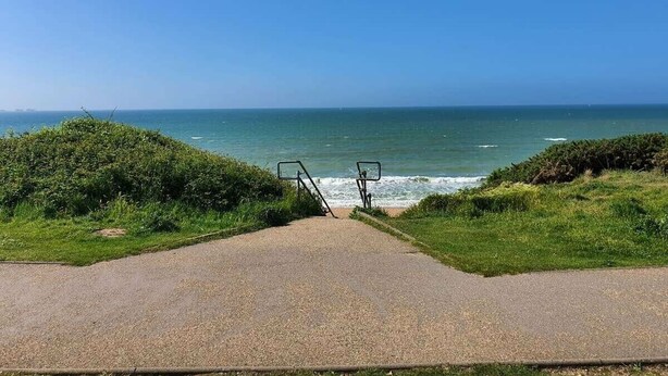 Un camino pavimentado que conduce a una playa con una vista despejada del océano.