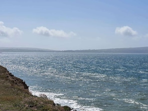Eine Küstenlandschaft mit freiem Blick auf das Meer und sanften Hügeln im Hintergrund.