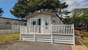 Una casa móvil con fachada blanca, un balcón y un patio cercado.
